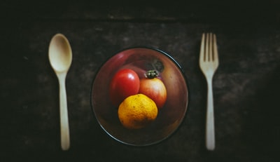 琥珀色玻璃碗，除了白色的勺子和叉子外还有水果